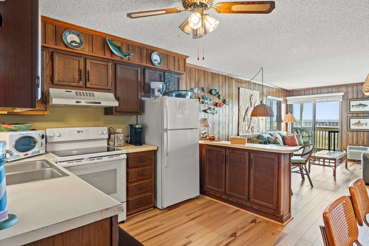 A view of the well-equipped kitchen with ample cabinetry, a dining table, and a window providing ocean views. The scene feels bright and welcoming, inviting guests to prepare meals or gather for casual dining with a scenic backdrop.