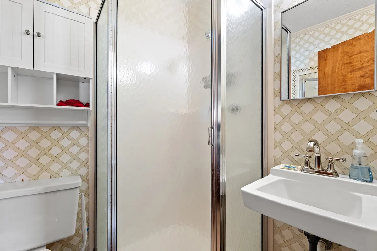 A fresh and inviting bathroom featuring a shower stall, sink, mirror, and storage cabinet. The space appears clean and well-lit, providing everything needed for personal routines and comfort.